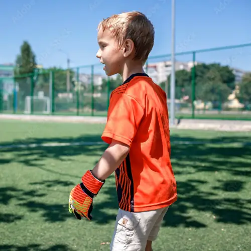 A small child in orange with gloves playing sports
